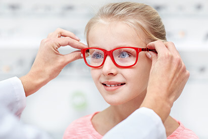Mädchen mit roter Kinderbrille beim Augenarzt